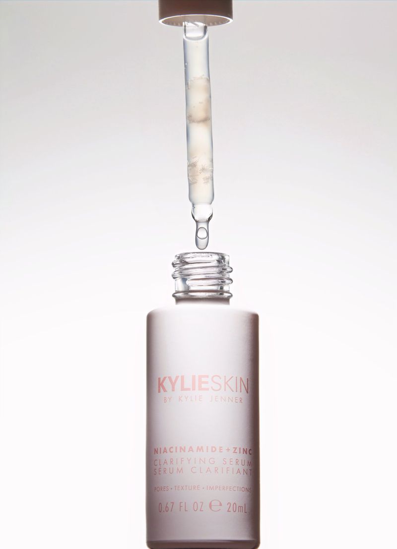 KylieSkin niacinamide serum bottle with a dropper dispensing liquid. White bottle and liquid against a plain white background.