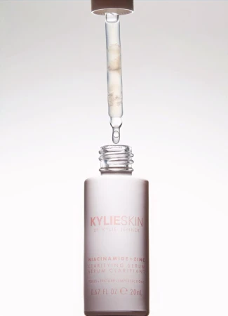 KylieSkin niacinamide serum bottle with a dropper dispensing liquid. White bottle and liquid against a plain white background.