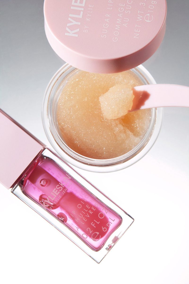 Cosmetic products including a lip scrub and lip oil by Kylie Cosmetics on a bright white background. Beauty product photography.