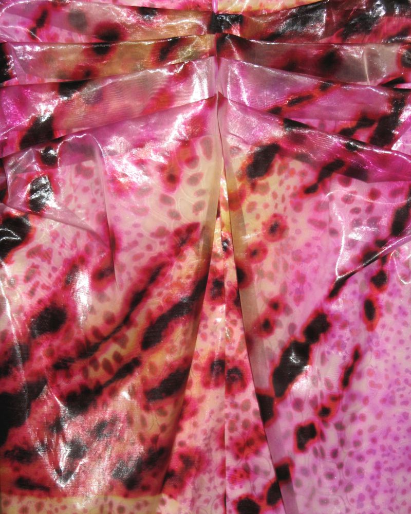 Close-up shot of a draped fabric with a pink, yellow, and black animal print pattern creating soft folds and interesting textures.