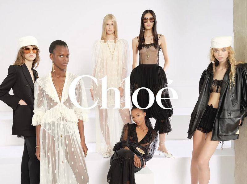 Group of fashion models presenting Chloé designs in a studio setting, wearing dresses, jackets, tops, and matching accessories.