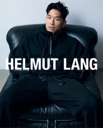Man seated in a black leather armchair wearing a black zip-up hoodie and matching pants for Helmut Lang Men Fall Winter 24 campaign