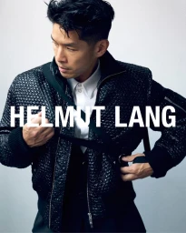 Man in a textured black bomber jacket over a white collared shirt against a white seamless background