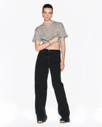 Model Aylah Peterson wearing a grey t-shirt and wide-leg black denim jeans posing against a white seamless backdrop.