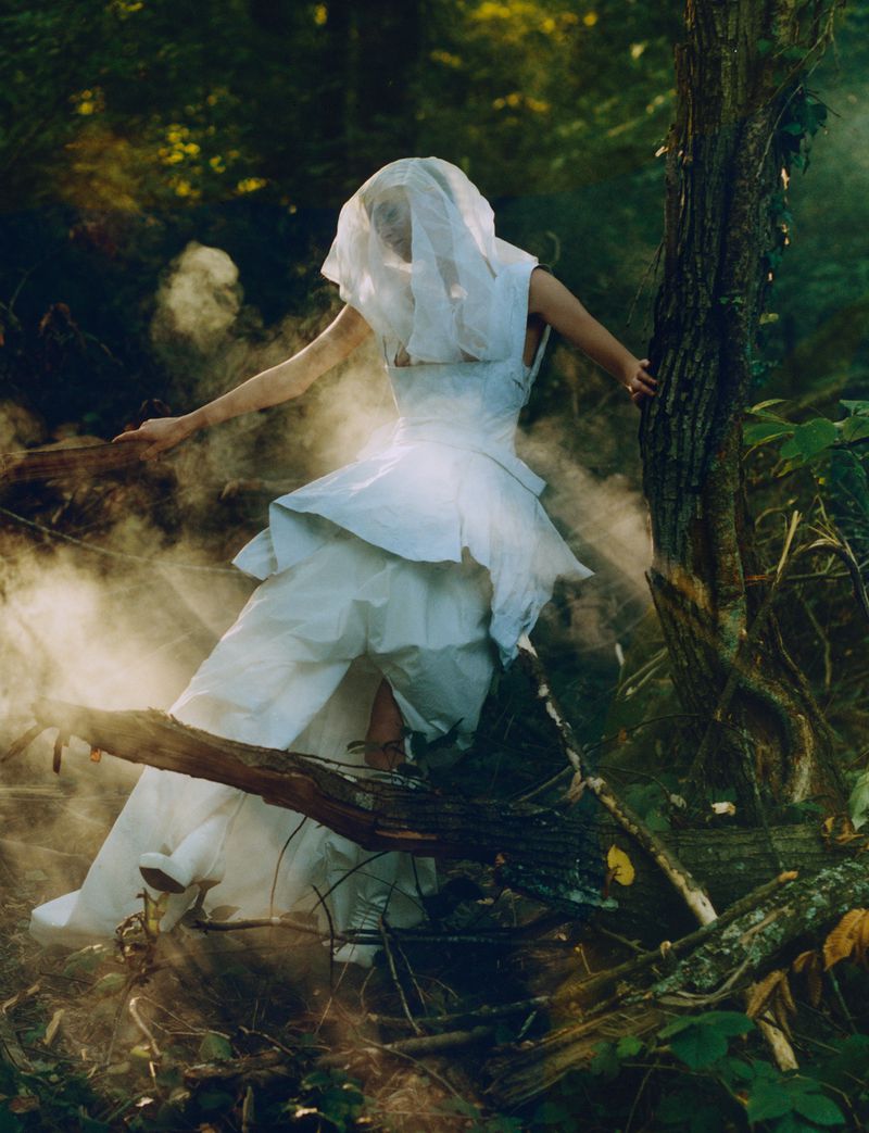 Model in a flowing white dress and veil standing in a misty forest for an editorial shoot by Overdue Magazine.