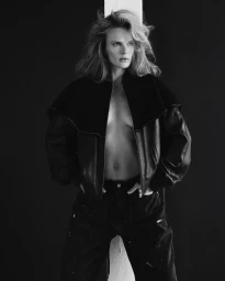 Monochrome fashion portrait of model Anne Vyalitsyna wearing an open black jacket against a dark background for SLIMI Magazine.