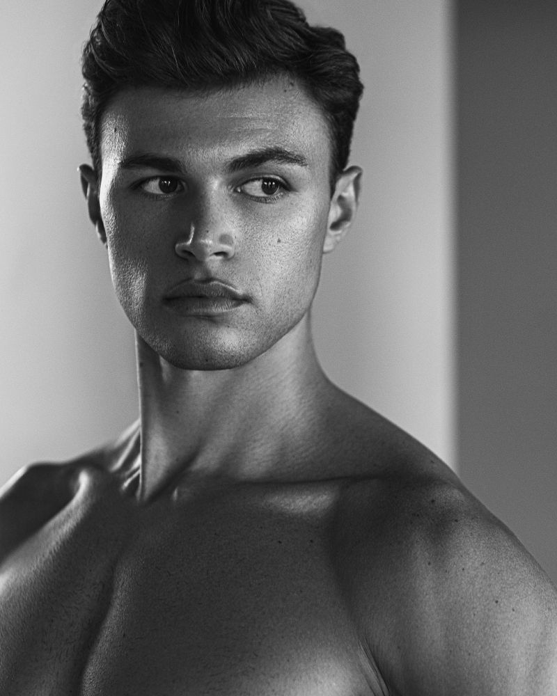 Monochrome portrait of a shirtless young man looking away in a studio setting