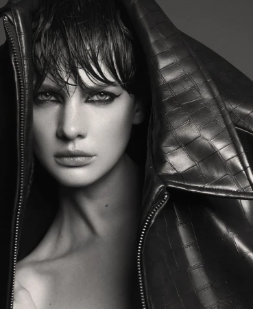 Close-up portrait of a woman with wet hair wearing a textured leather jacket pulled up over her head, shot in monochrome.