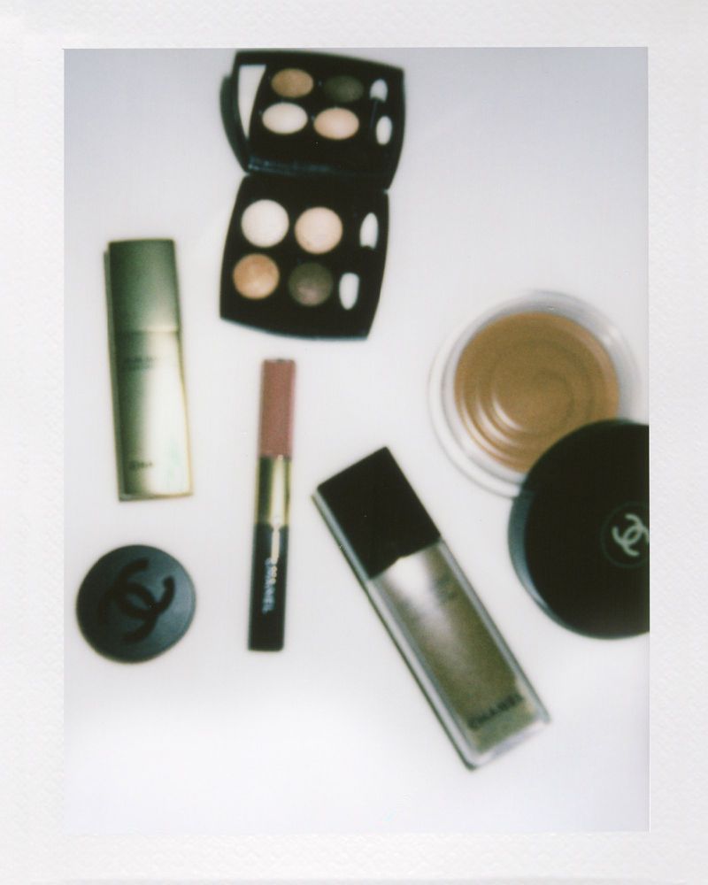 A collection of Chanel brand makeup products including eyeshadow palette, foundation, concealer, and powder arranged on a white surface.