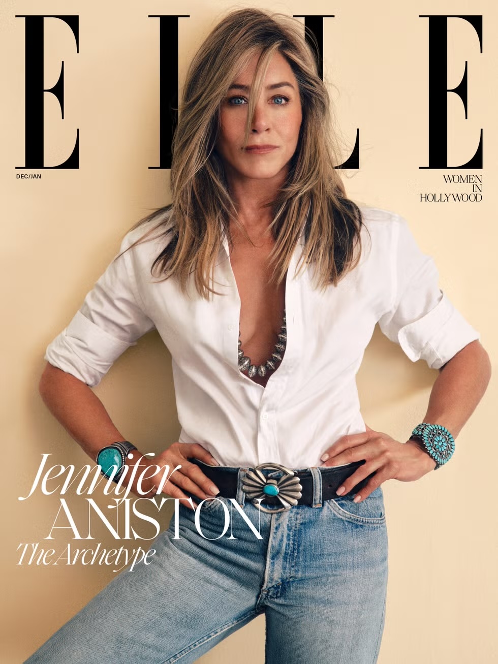 Jennifer Aniston poses on the cover of ELLE magazine, wearing a white shirt, blue jeans, and turquoise jewelry against a neutral backdrop.