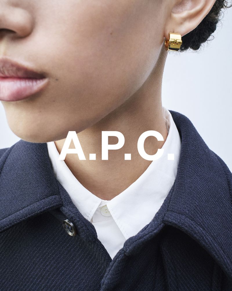 Close-up of a woman wearing gold hoop earrings with a navy coat and white collared shirt, showcasing fashion and jewellery.