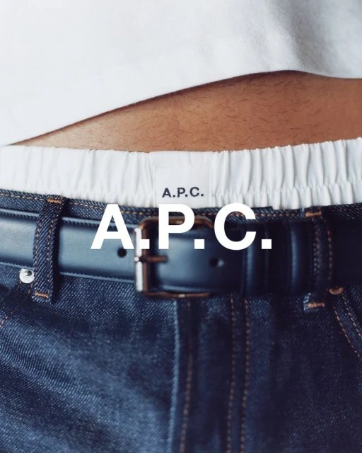 A close-up shot of dark blue jeans with a black leather belt, a white t-shirt waistband and A.P.C. logo.