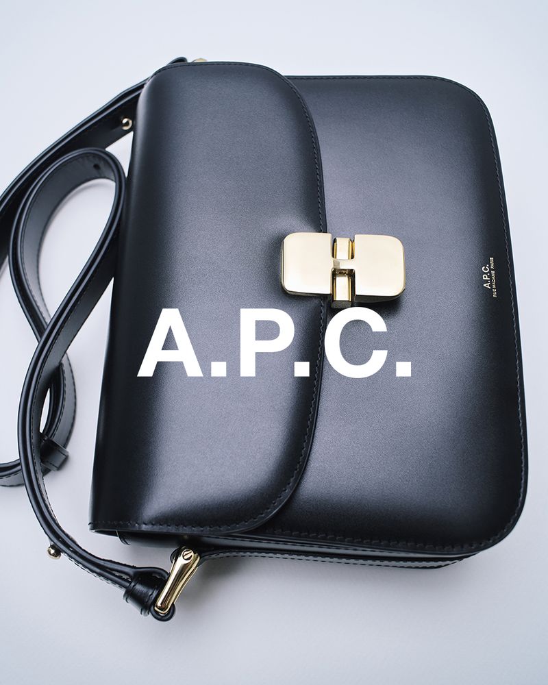 A black A.P.C. leather bag with a gold clasp and shoulder strap, presented against a white background in a studio setting.