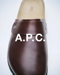 Close-up product shot of a dark brown leather mule shoe with metal rivets on a plain white background