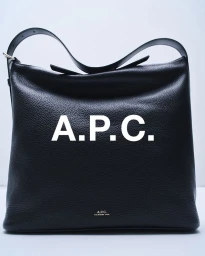 Black leather shoulder bag with bold white A.P.C. branding against a clean white seamless studio background.