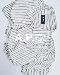 Folded white and black striped button-down shirt with a visible A.P.C. label on a seamless light grey background
