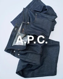 Folded dark indigo denim jeans arranged against a plain light background with large white branding text overlay