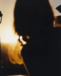 Silhouette of a person against a bright sunset sky with backlit hair glowing in the golden light.