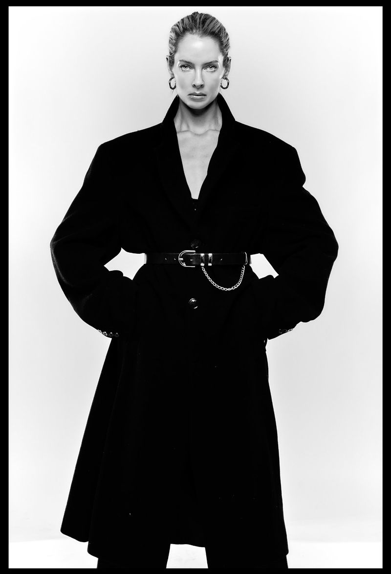 Model Emily Fay wearing a black belted coat against a white background for a studio portrait photographed by Oscar Ozbay.