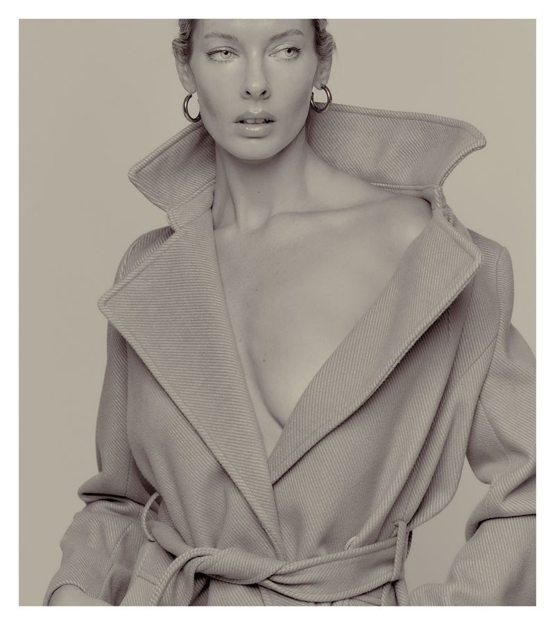 Monochrome portrait of a woman in a coat with large hoop earrings, neutral background, shallow depth of field, dramatic lighting.