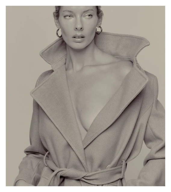 Monochrome portrait of a woman in a coat with large hoop earrings, neutral background, shallow depth of field, dramatic lighting.