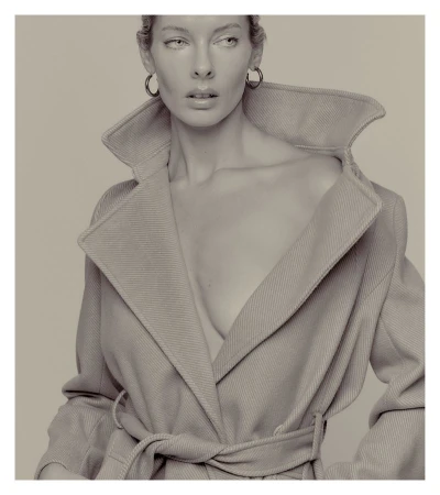 Monochrome portrait of a woman in a coat with large hoop earrings, neutral background, shallow depth of field, dramatic lighting.