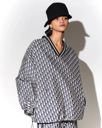 Model Lineisy Montero wearing a black bucket hat and Dior patterned top against a white studio background.