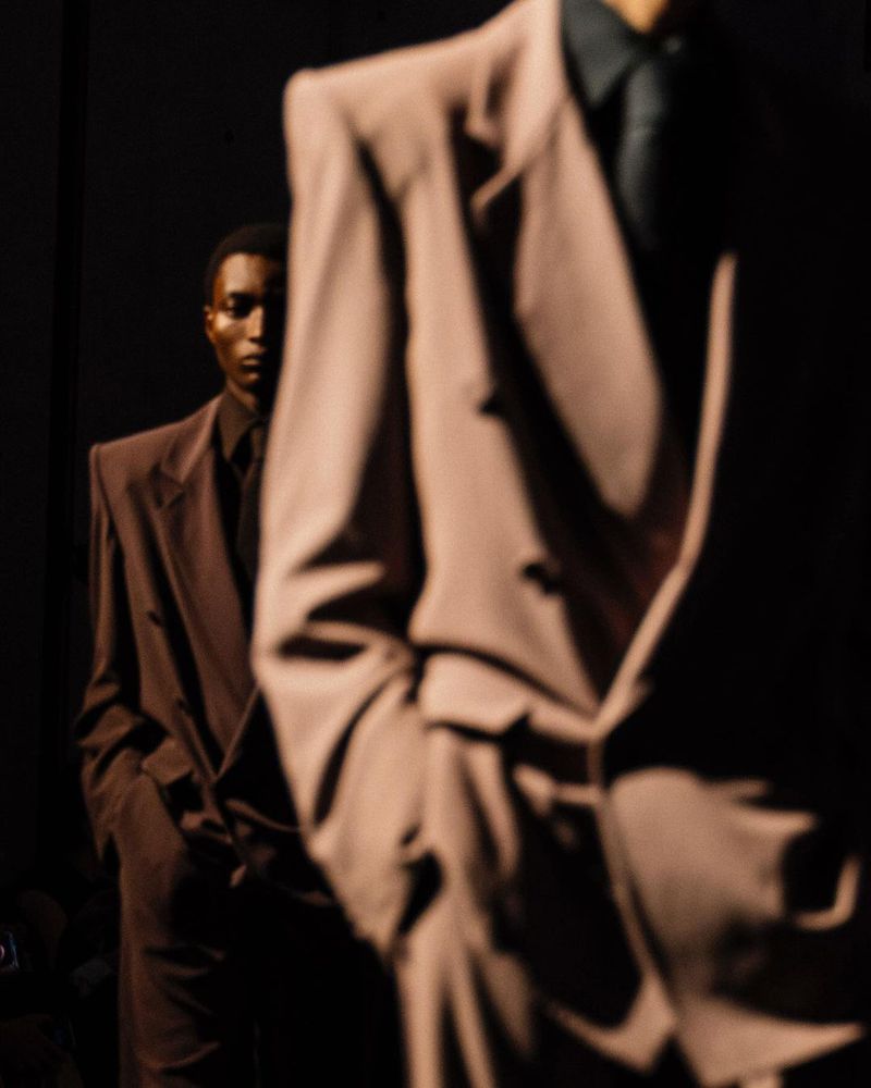 Two African American men in oversized suits in a dark setting, fashion photography. Brown suit jacket, dress shirt and tie.