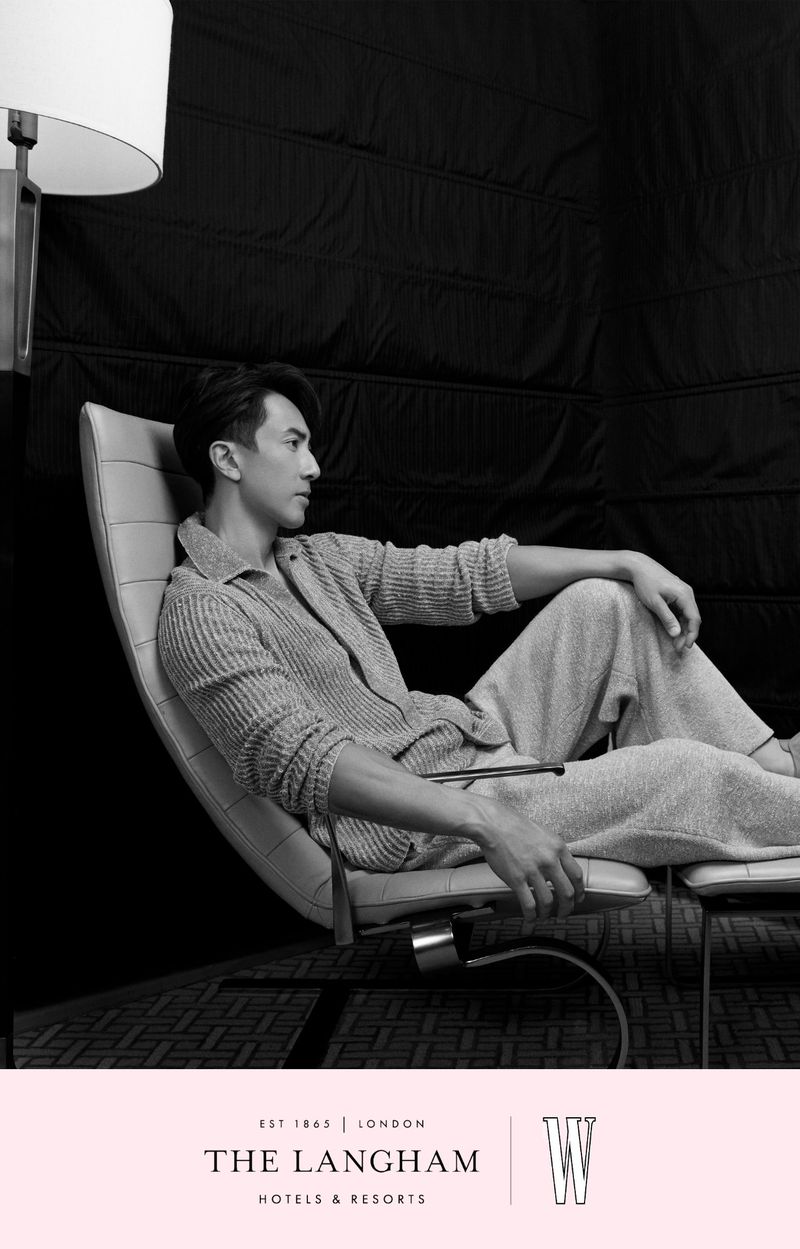 Monochrome portrait of an Asian man seated in a modern lounge chair next to a floor lamp, for W Magazine China.
