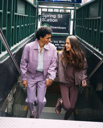 A stylish couple in matching outfits descends subway stairs, captured in medium shot, showcasing fashion and urban life with soft lighting.