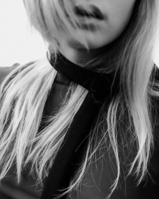 Close-up black and white portrait of a woman with light blonde hair and a black choker, showcasing beauty and fashion.