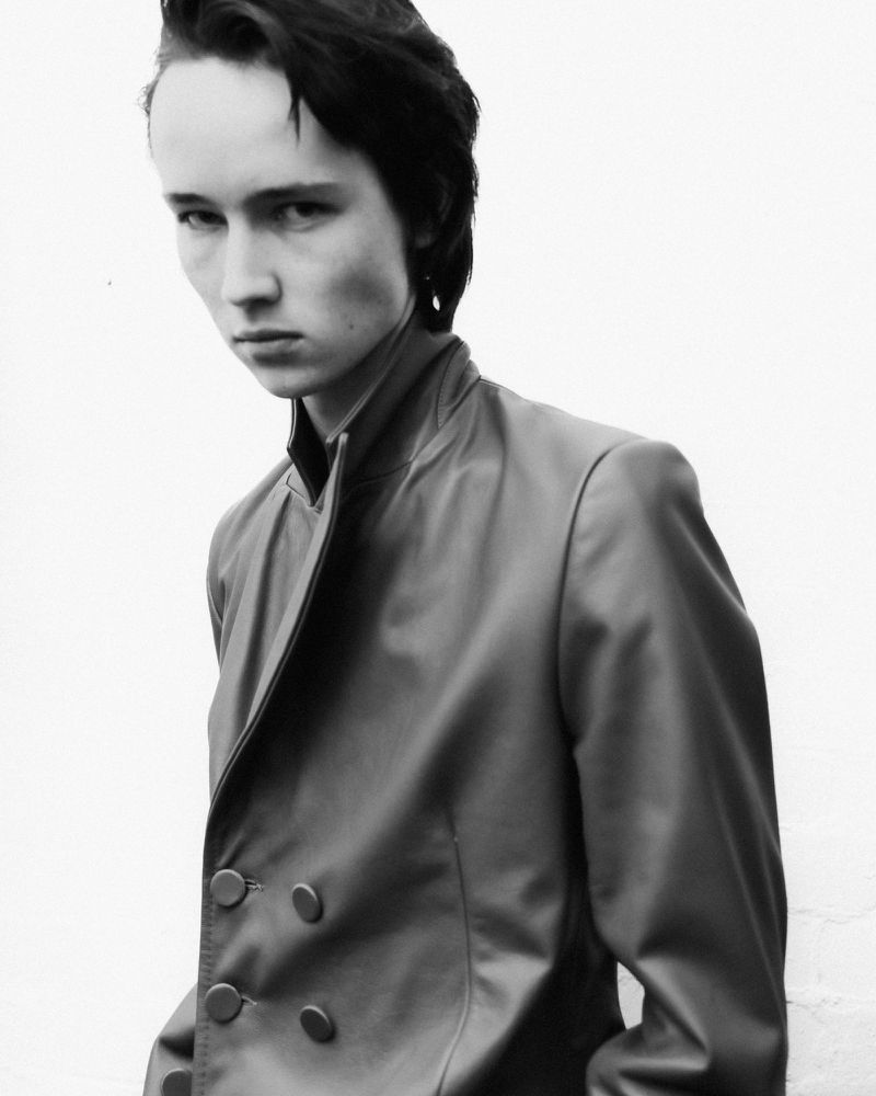 Monochrome portrait of a model wearing a structured jacket against a plain light background for Aaron Esh A/W 24