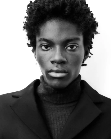 Portrait of a black man wearing a dark turtleneck and blazer against a plain white background