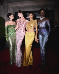 Four models in glittering gowns standing on a red carpet for Swarovski at the MET Gala 2024, photographed by Luca Stefanon.