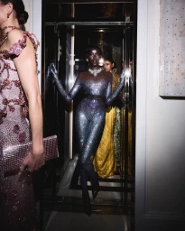 Model Anok Yai in a glittering crystal catsuit standing in an elevator doorway for Swarovski at the Met Gala 2024.