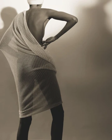 Model wearing a textured knitted cashmere wrap against a light studio wall with soft directional shadows
