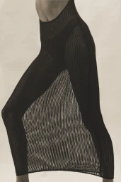 Close-up profile of a model wearing black ribbed knit trousers against a neutral background.