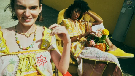 Two women in yellow patterned garments posing outdoors with yellow florals for Alemais CELEBRACIÓN campaign.
