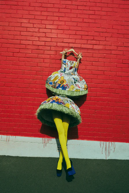A brightly colored dress and stockinged legs are displayed against a vibrant red brick wall, creating an eye-catching fashion statement.