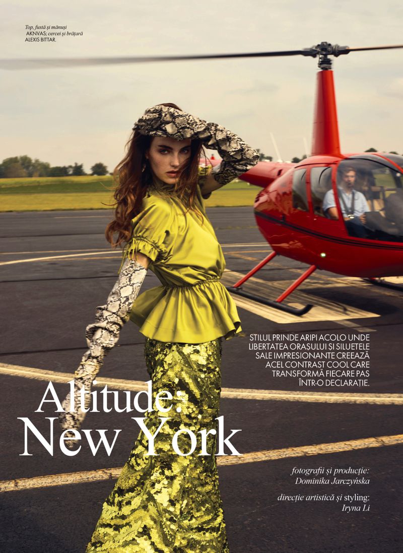 Fashion editorial shoot featuring a female model in a green dress and snake print accessories, posing in front of a red helicopter on a runway.