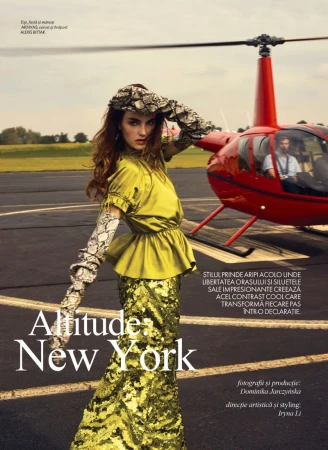 Fashion editorial shoot featuring a female model in a green dress and snake print accessories, posing in front of a red helicopter on a runway.