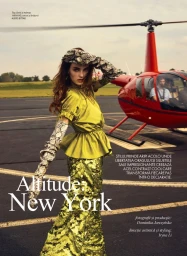 Model wearing a chartreuse silk top and sequined skirt with snakeskin gloves standing beside a red helicopter