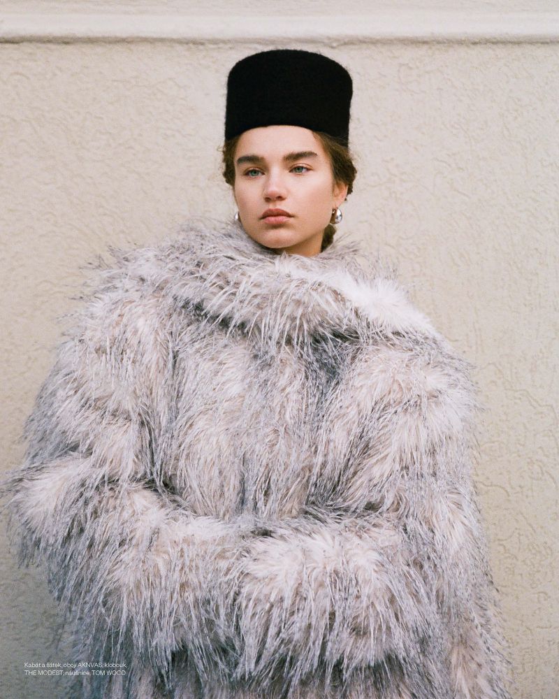 Meghan Roche wearing a fluffy textured coat and black hat against a neutral wall for Vogue Czechoslovakia