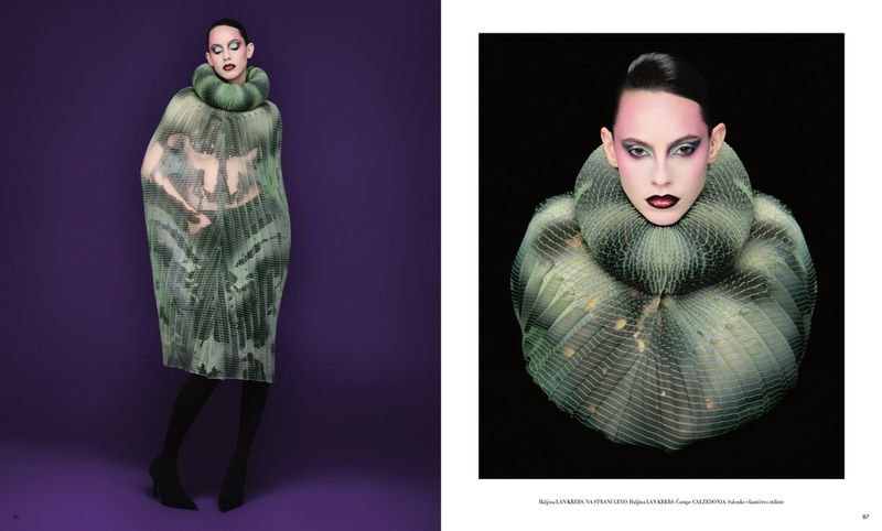 Fashion editorial shot of a woman in a green and grey dress with a large ruffled collar on a purple background in a studio.
