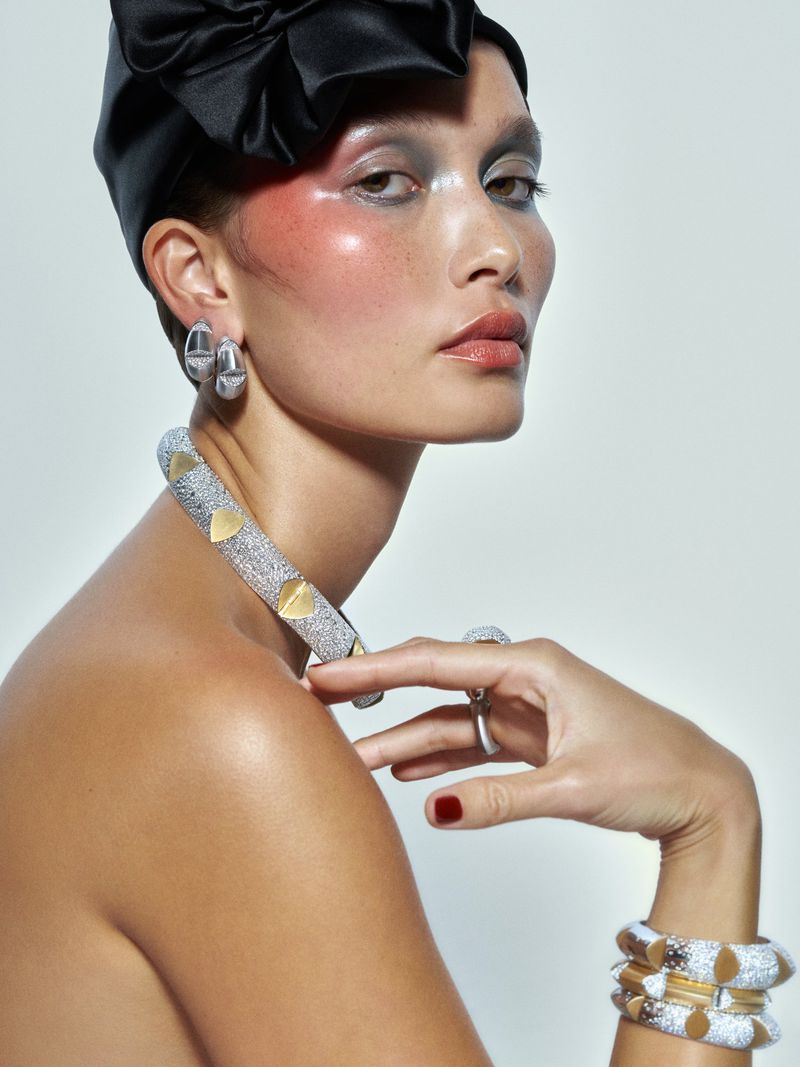 Portrait of a woman wearing a black headscarf, sparkling choker necklace, and matching bracelets against a neutral backdrop in a studio.
