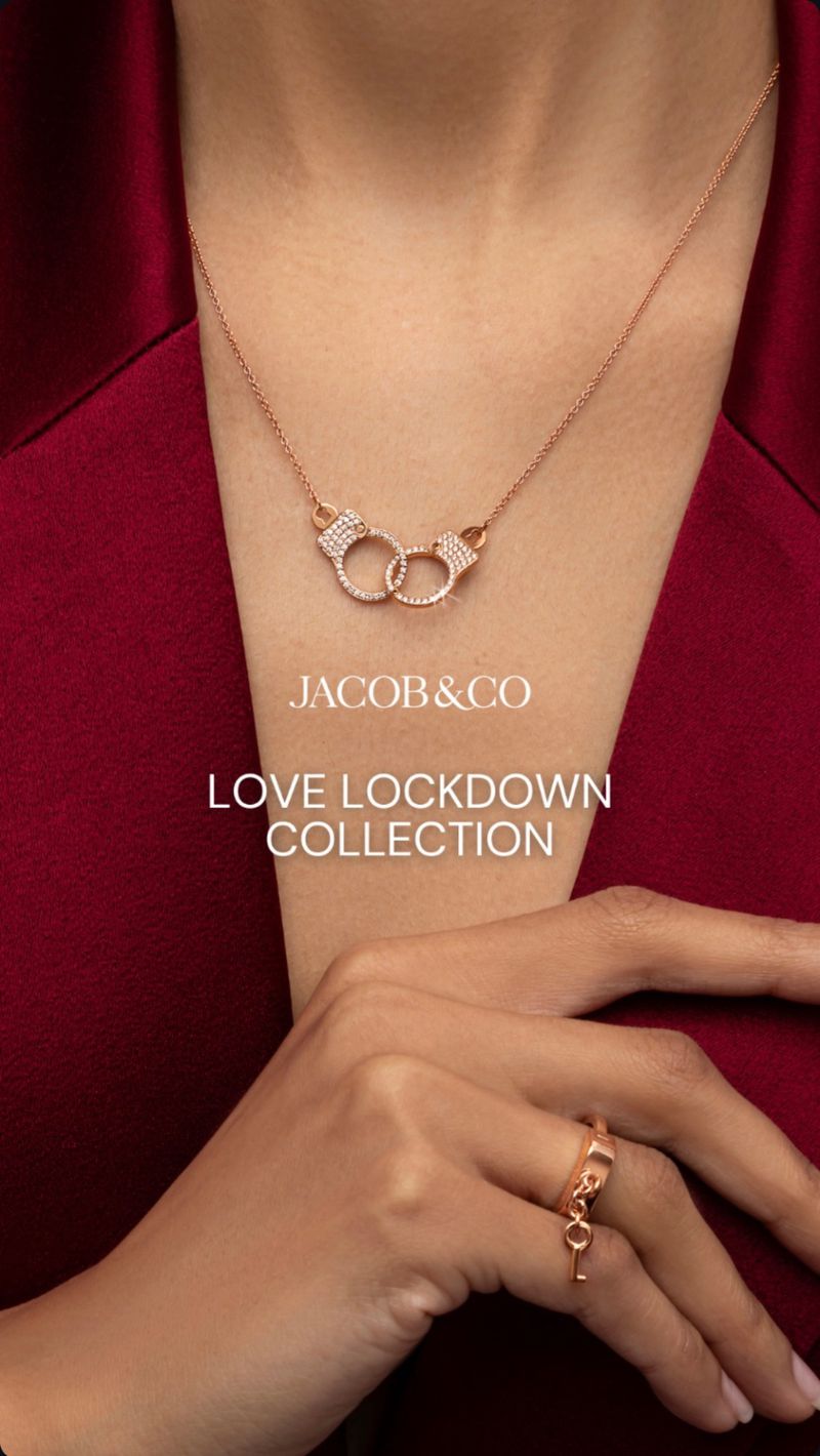 Necklace and ring jewellery from Jacob & Co's Love Lockdown Collection, worn with a red shirt, accessorising the hands and neck.