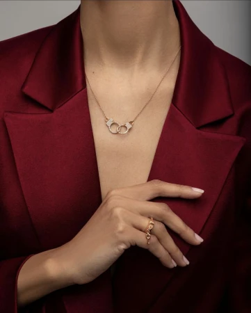 Model wearing a deep red blazer, diamond necklace, and ring against a neutral studio background