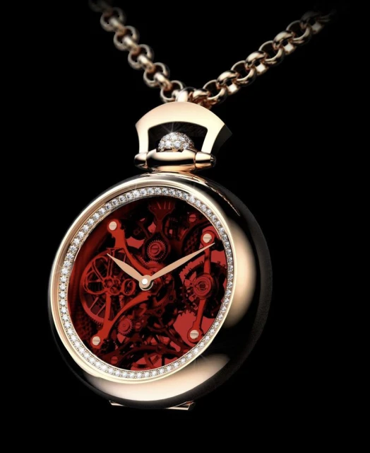 Elegant gold pendant watch on a chain, featuring a diamond-studded bezel and a detailed red clockwork mechanism against a black backdrop.