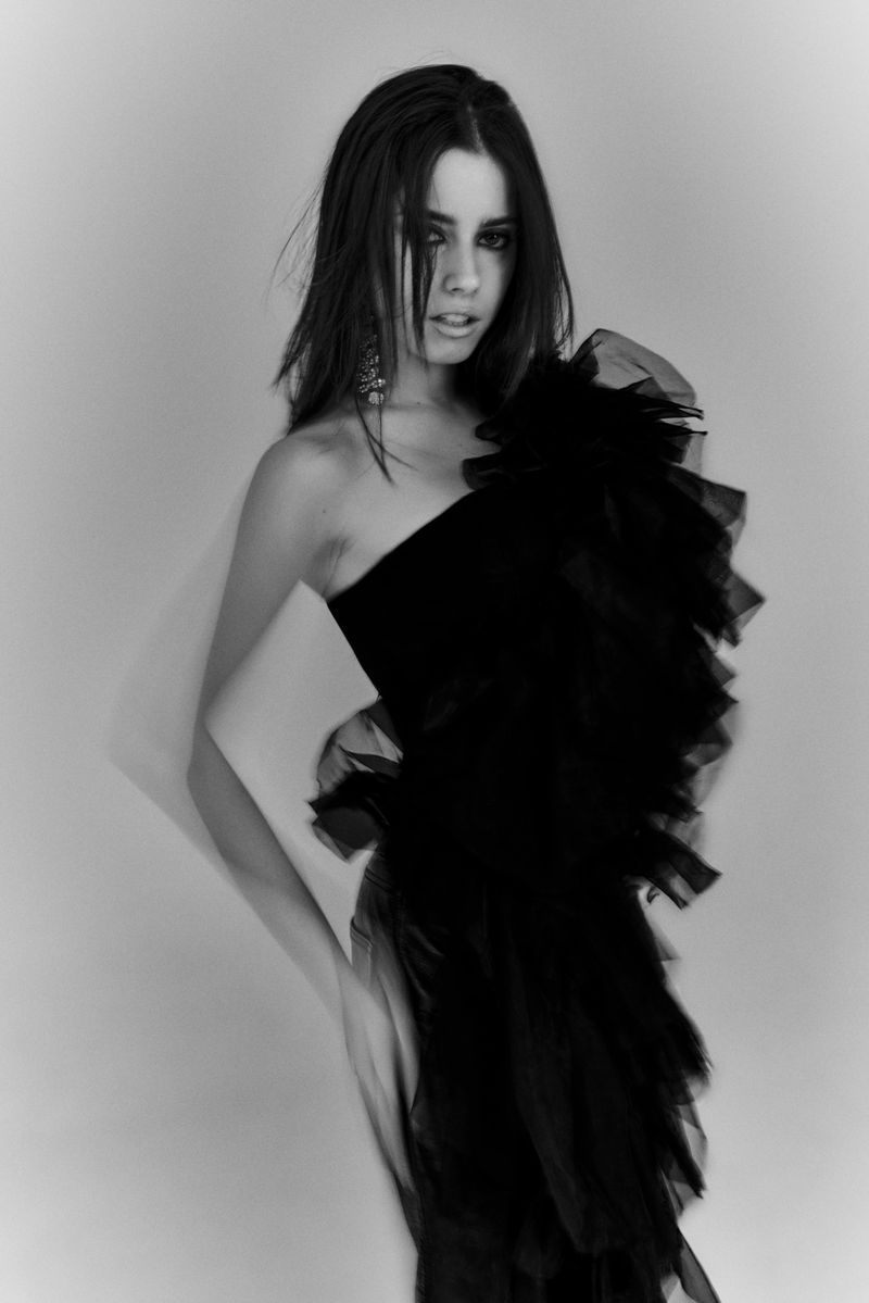 Portrait of Madalena Aragao in a black ruffled dress against a plain studio background for Numero Netherlands.