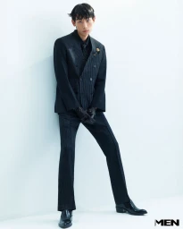 Model Min Seok Choi in a dark pinstripe suit and leather gloves posing against a pale seamless studio background for Noblesse Korea.